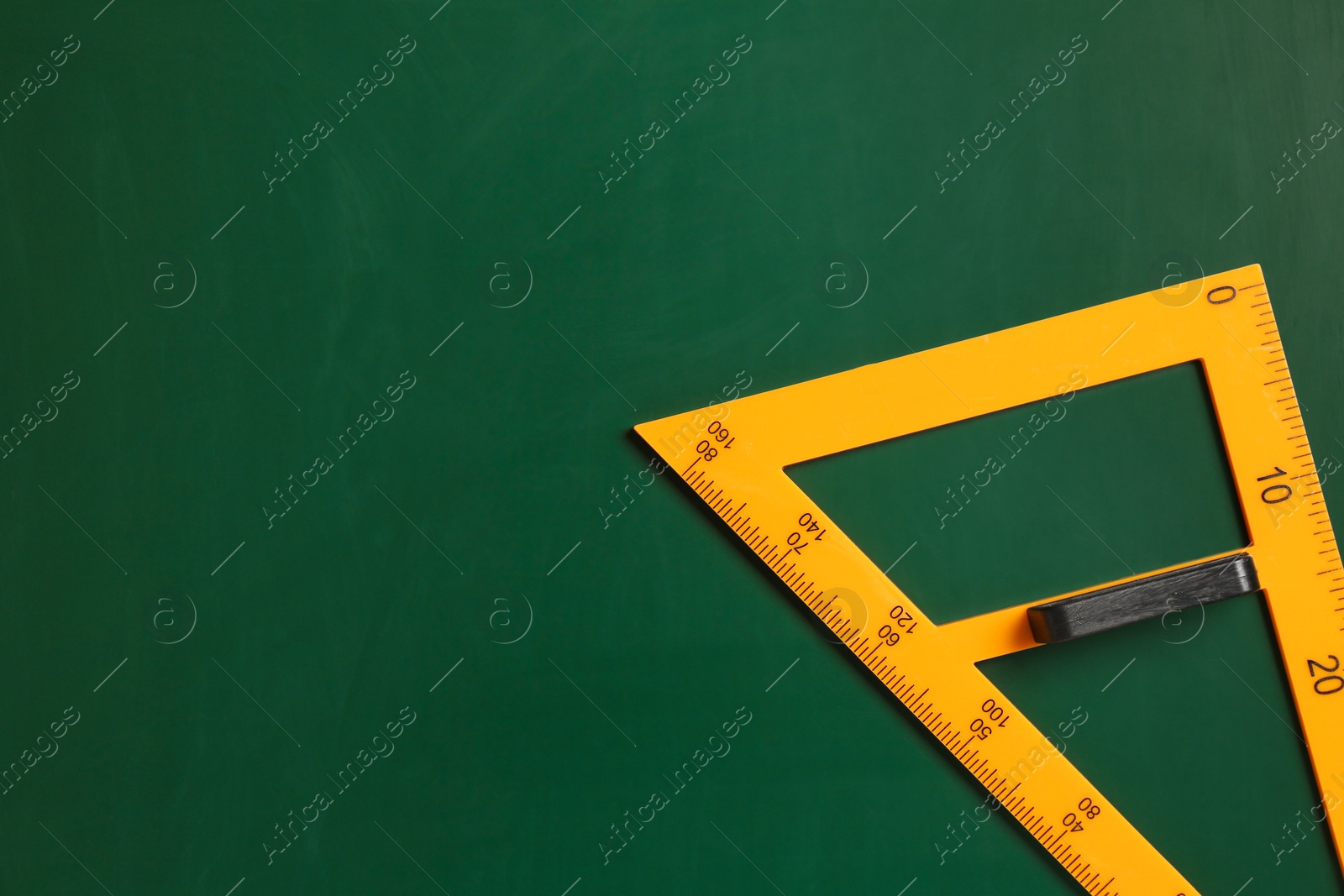 Photo of One triangle ruler on green chalkboard, top view. Space for text