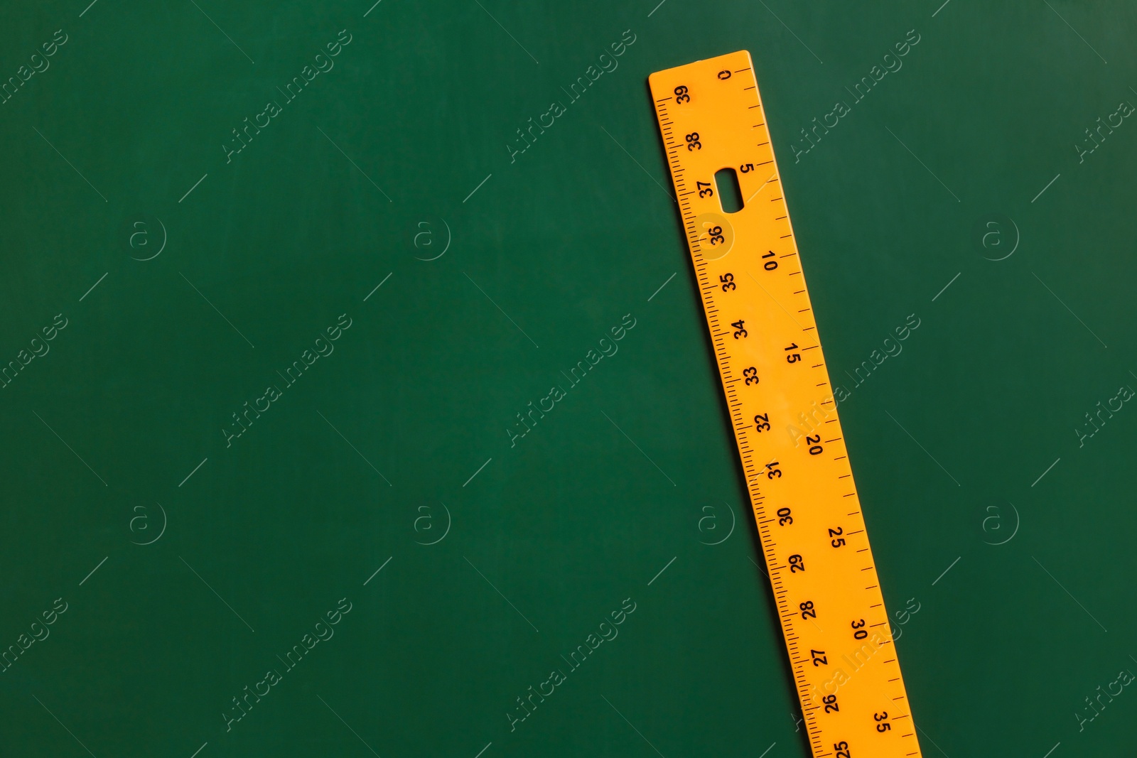 Photo of One ruler on green chalkboard, top view. Space for text