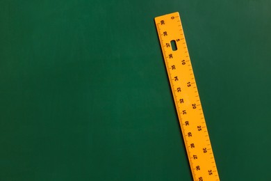 Photo of One ruler on green chalkboard, top view. Space for text