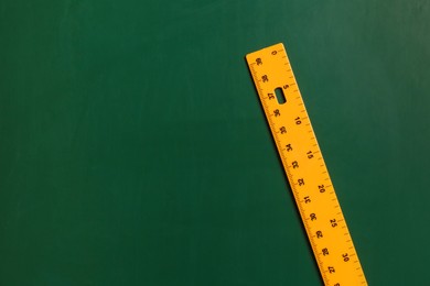 Photo of One ruler on green chalkboard, top view. Space for text