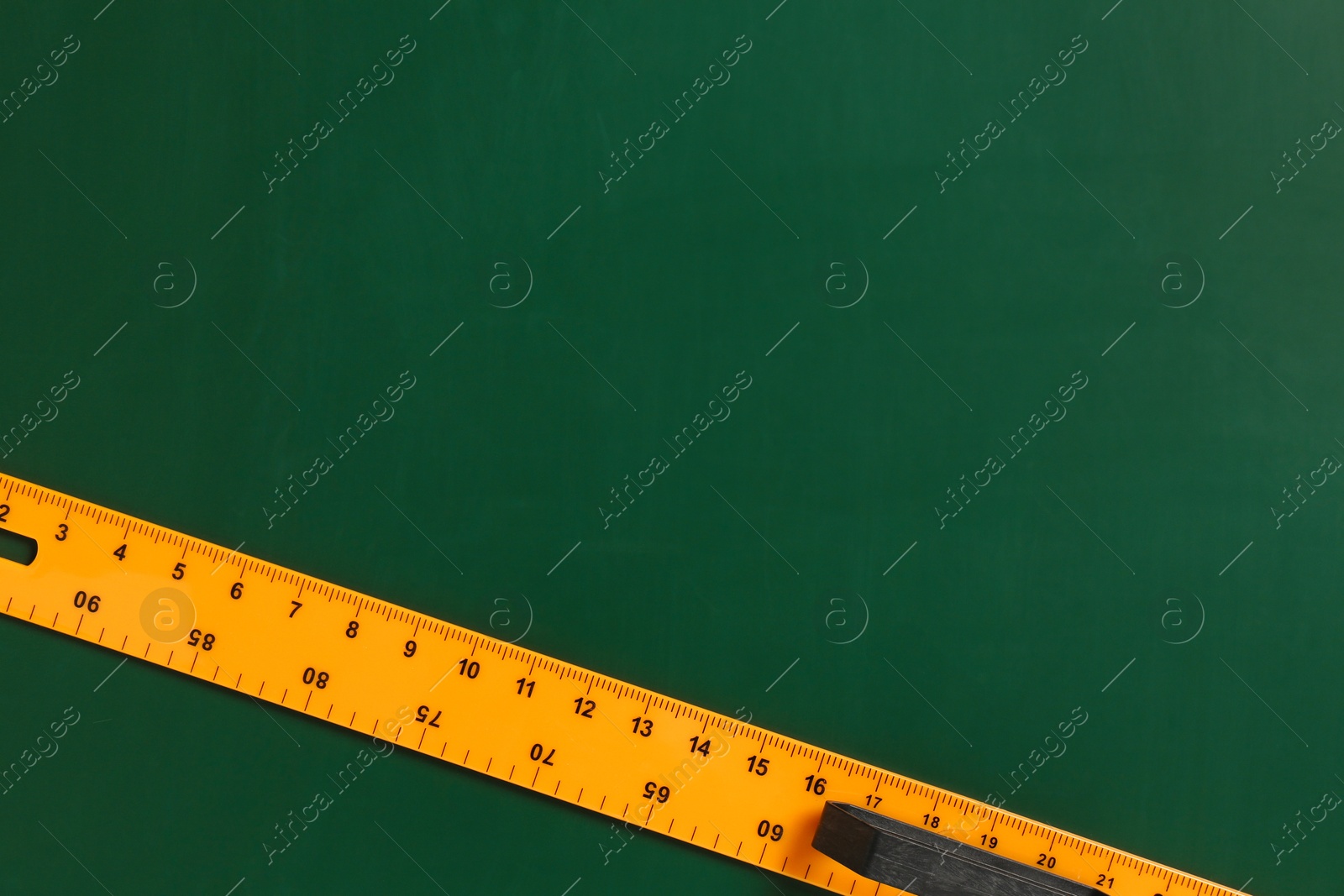 Photo of One ruler on green chalkboard, top view. Space for text