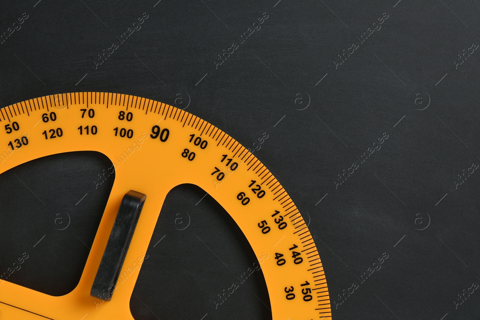 Photo of Protractor ruler on black chalkboard, top view. Space for text