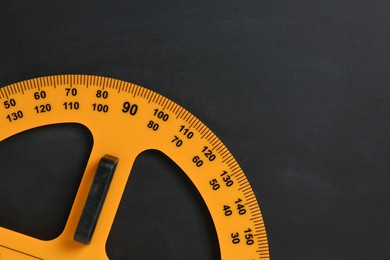 Photo of Protractor ruler on black chalkboard, top view. Space for text