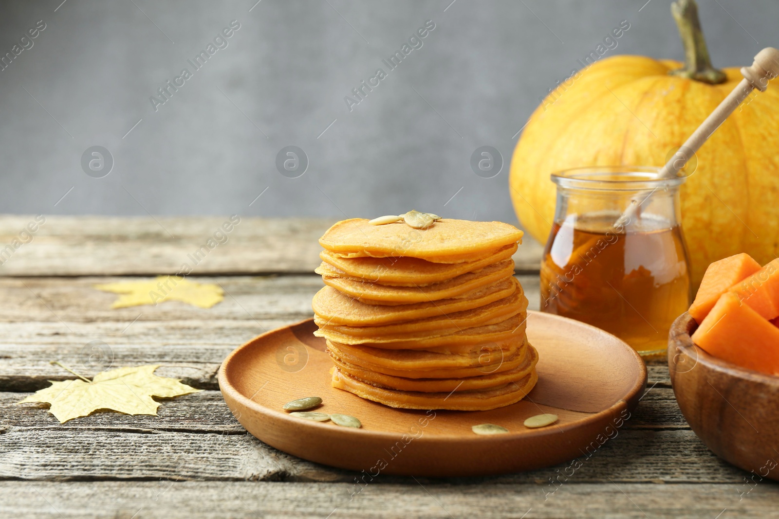 Photo of Tasty pumpkin pancakes with seeds served on wooden table