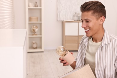 Photo of Smiling decorator arranging nightlight onto shelf indoors