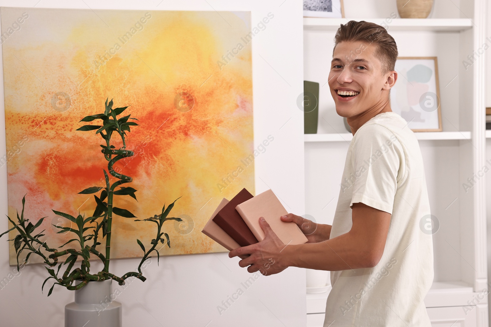 Photo of Smiling young male decorator with books indoors