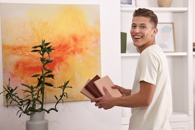 Photo of Smiling young male decorator with books indoors