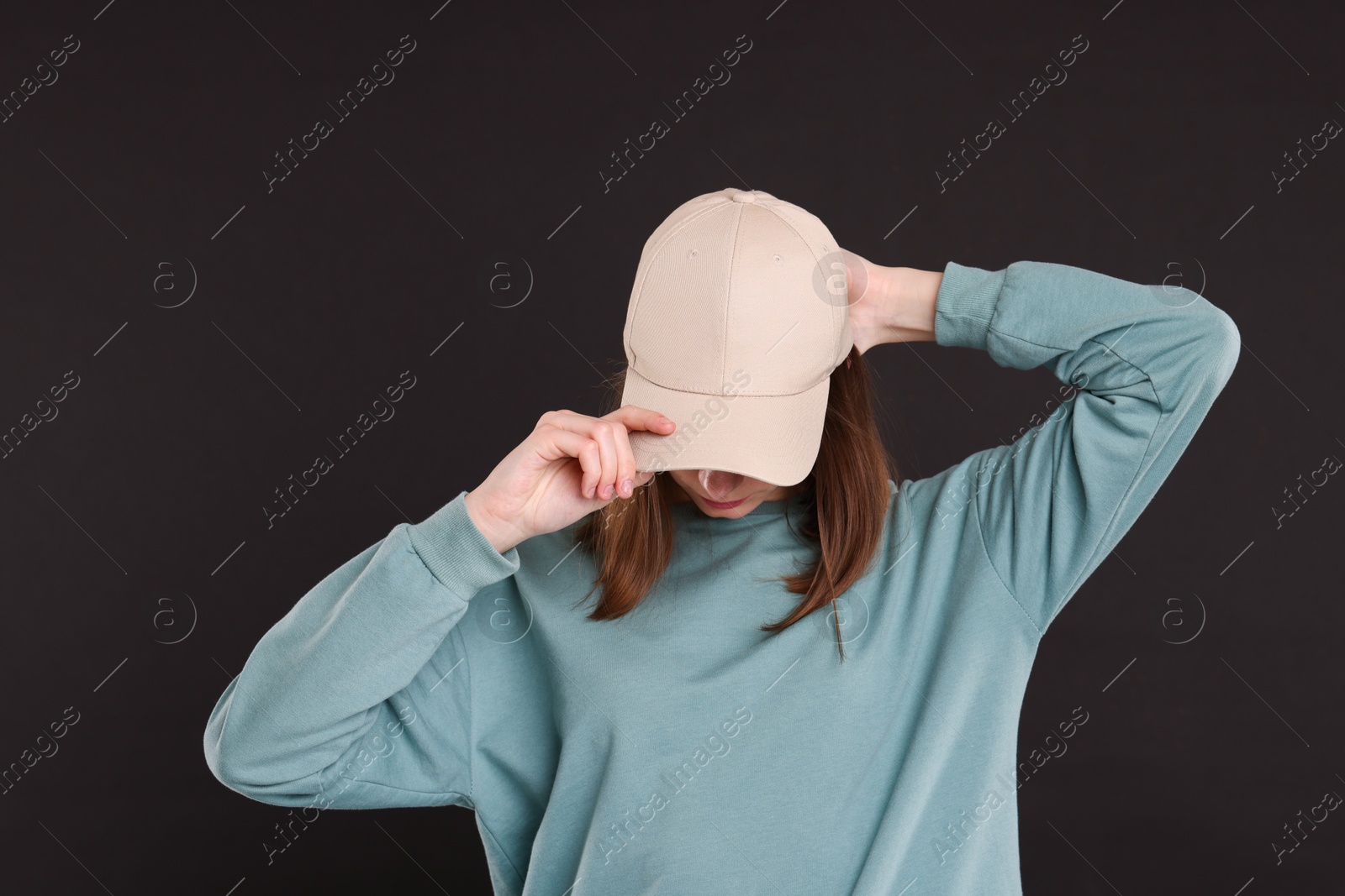 Photo of Woman in stylish baseball cap on black background. Mockup for design