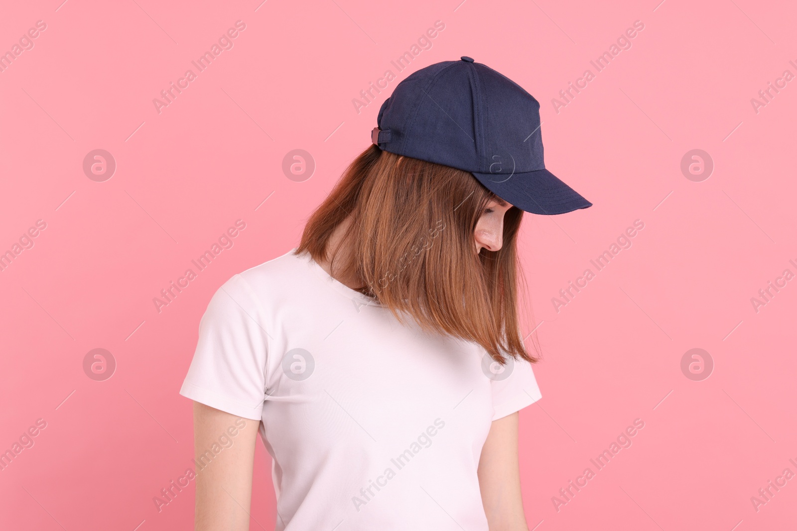 Photo of Woman in stylish baseball cap on pink background. Mockup for design