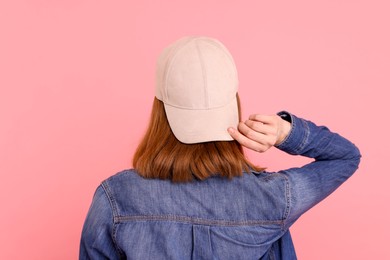 Photo of Woman in stylish baseball cap on pink background, back view. Mockup for design