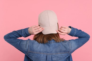 Photo of Woman in stylish baseball cap on pink background, back view. Mockup for design