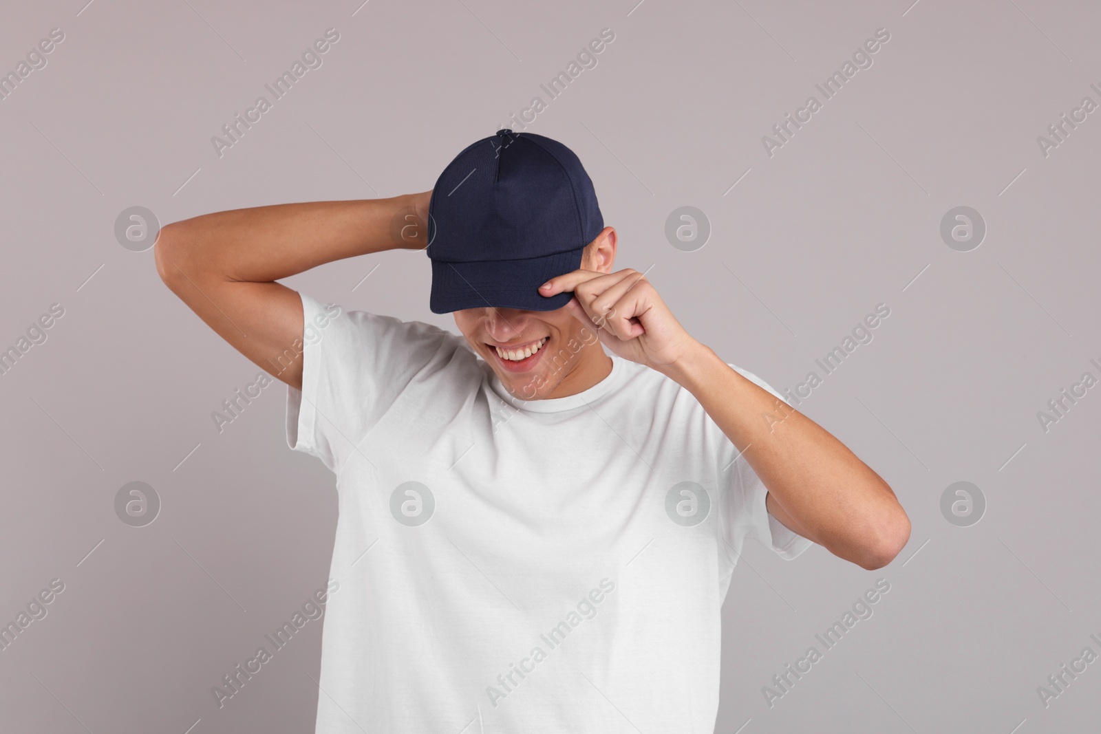 Photo of Smiling man in stylish baseball cap on grey background. Mockup for design