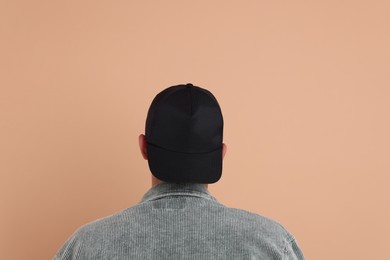 Photo of Man in stylish baseball cap on beige background, back view. Mockup for design