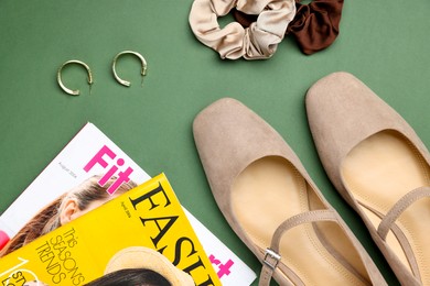 Pair of ballet flats, magazines and accessories on green background, flat lay