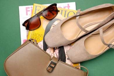 Photo of Pair of ballet flats, magazines and accessories on green background, flat lay