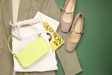 Photo of Pair of ballet flats, clothes, baguette bag and magazine on green background, top view