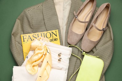 Photo of Pair of ballet flats, clothes, baguette bag and magazine on green background, top view