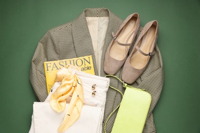 Photo of Pair of ballet flats, clothes, baguette bag and magazine on green background, top view