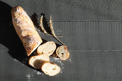 Photo of Pieces of fresh baguette with flour and spikes on grey wooden table, flat lay. Space for text