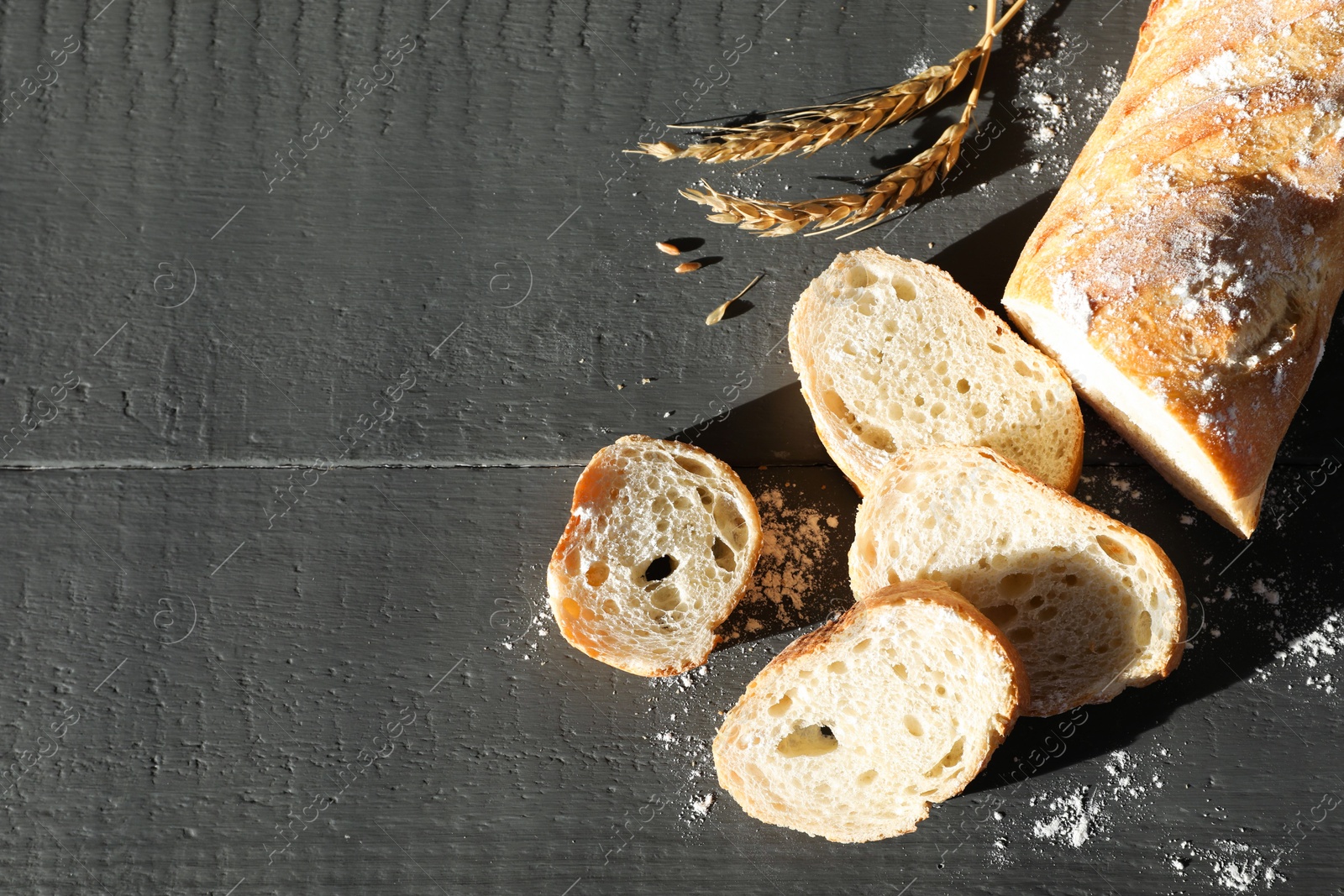 Photo of Pieces of fresh baguette with flour and spikes on grey wooden table, flat lay. Space for text