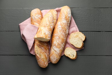 Photo of Cut fresh baguettes on grey wooden table, top view