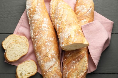 Photo of Cut fresh baguettes on grey wooden table, top view