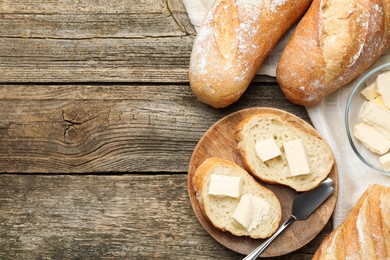 Photo of Slices of fresh baguette with butter on wooden table, flat lay. Space for text