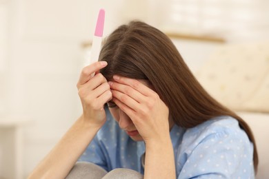 Photo of Upset woman with negative pregnancy test at home