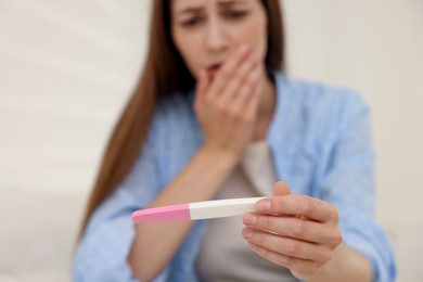 Photo of Upset woman with negative pregnancy test at home, selective focus