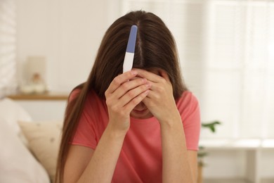 Photo of Upset woman with negative pregnancy test at home