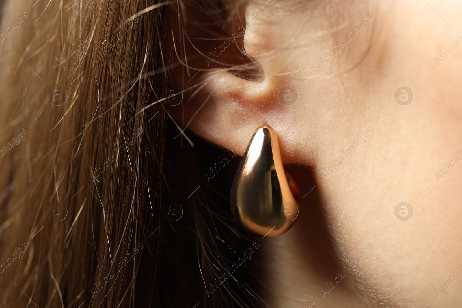 Photo of Woman wearing beautiful golden earring, closeup view