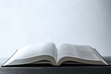 Photo of Open Holy Bible in English language on wooden table. Space for text