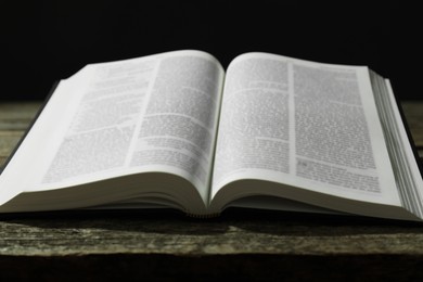 Photo of Open Holy Bible in English language on wooden table, closeup