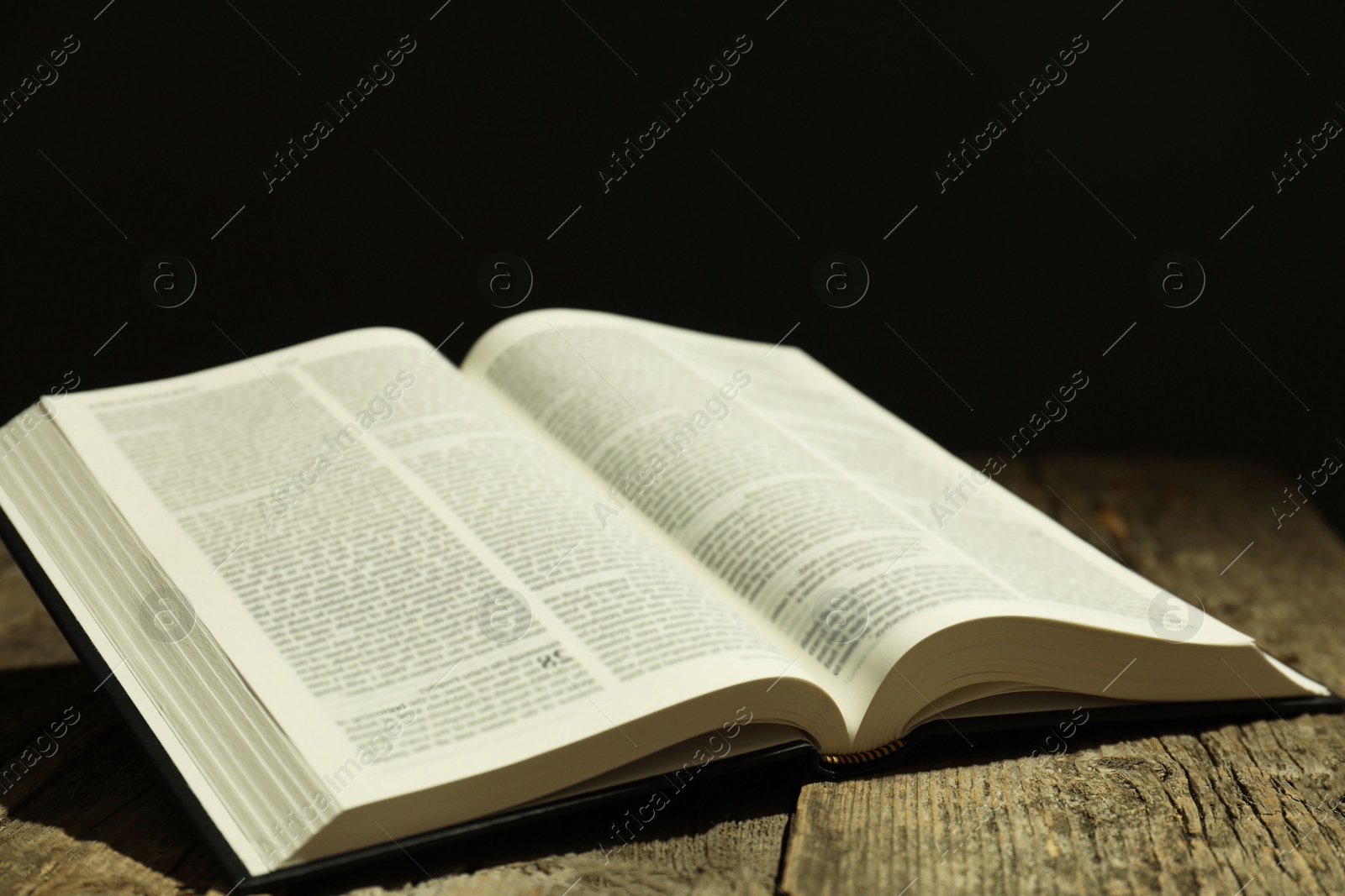 Photo of Open Holy Bible in English language on wooden table