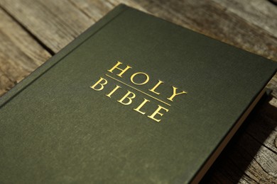 Hardcover Holy Bible on wooden table, closeup