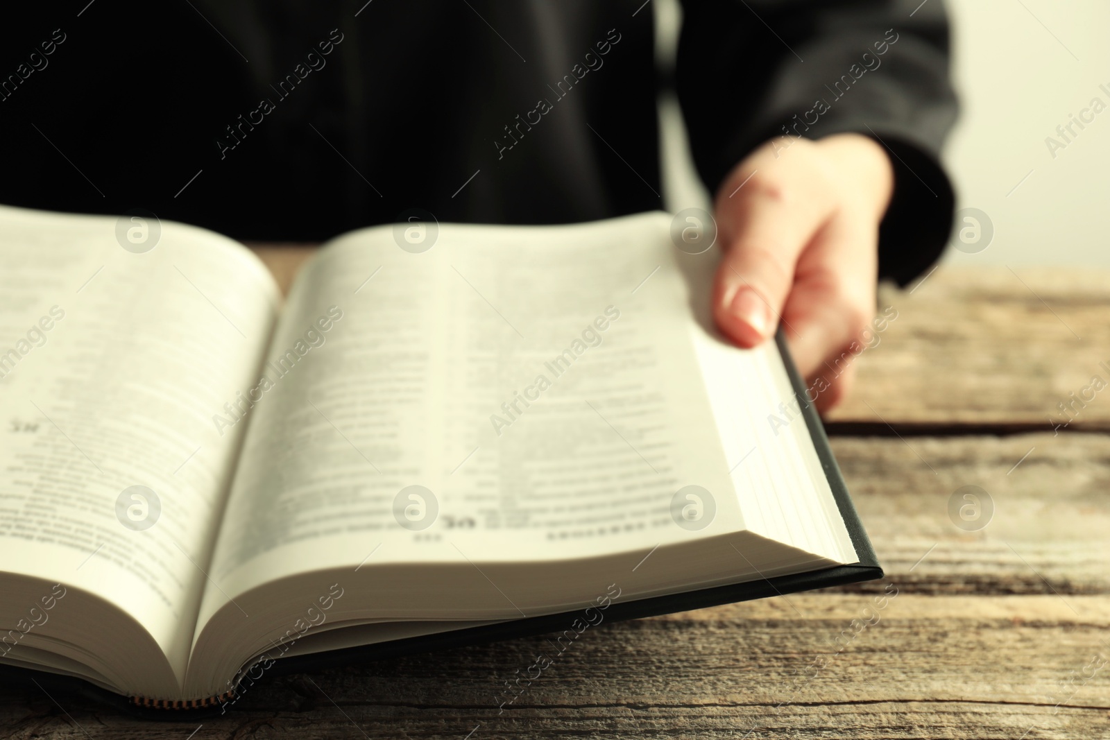 Photo of Woman with Holy Bible at wooden table, closeup