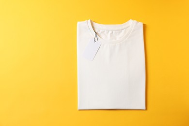 Photo of Blank white t-shirt on yellow background, top view. Mockup for design