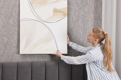 Photo of Female decorator hanging abstract picture in room