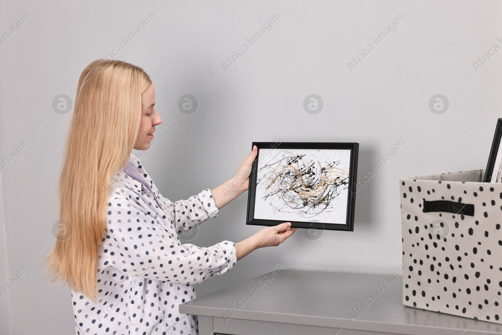 Photo of Smiling decorator with abstract picture near wall indoors