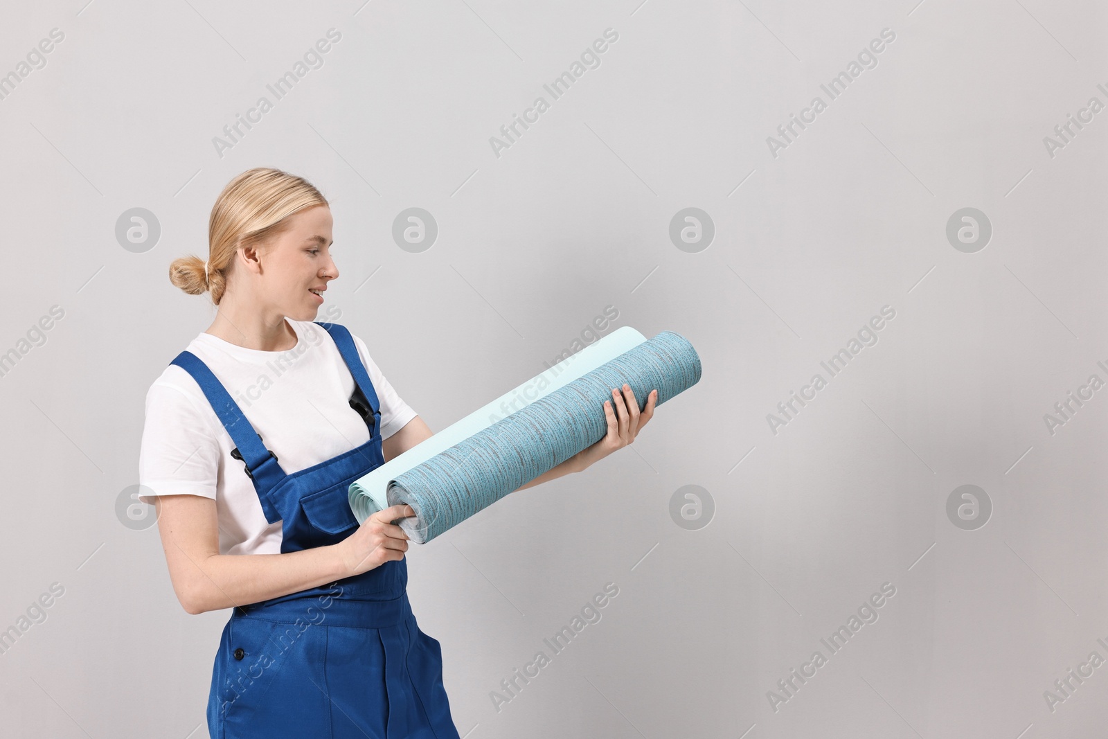 Photo of Smiling worker with rolls of wallpapers indoors, space for text