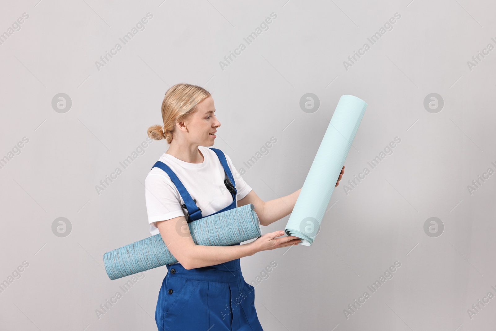 Photo of Smiling worker with rolls of wallpapers indoors