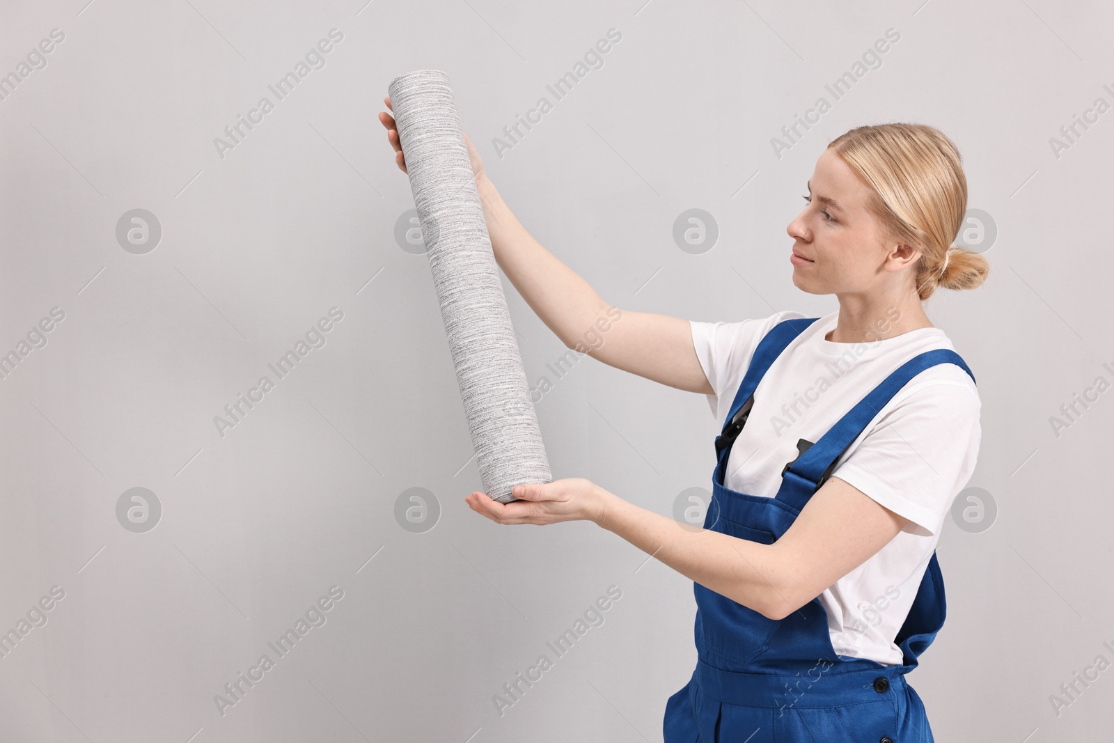 Photo of Female worker with roll of wallpaper indoors, space for text