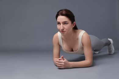 Photo of Woman in sportswear exercising on grey background, space for text