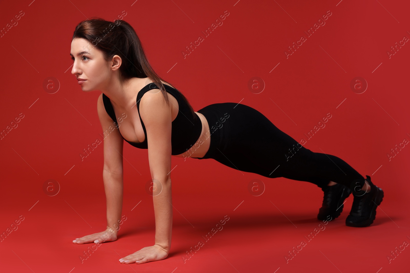 Photo of Woman in sportswear exercising on red background