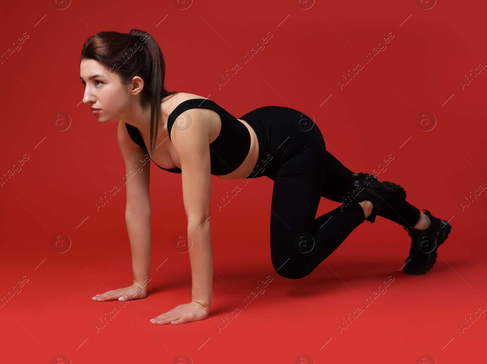 Photo of Woman in sportswear exercising on red background