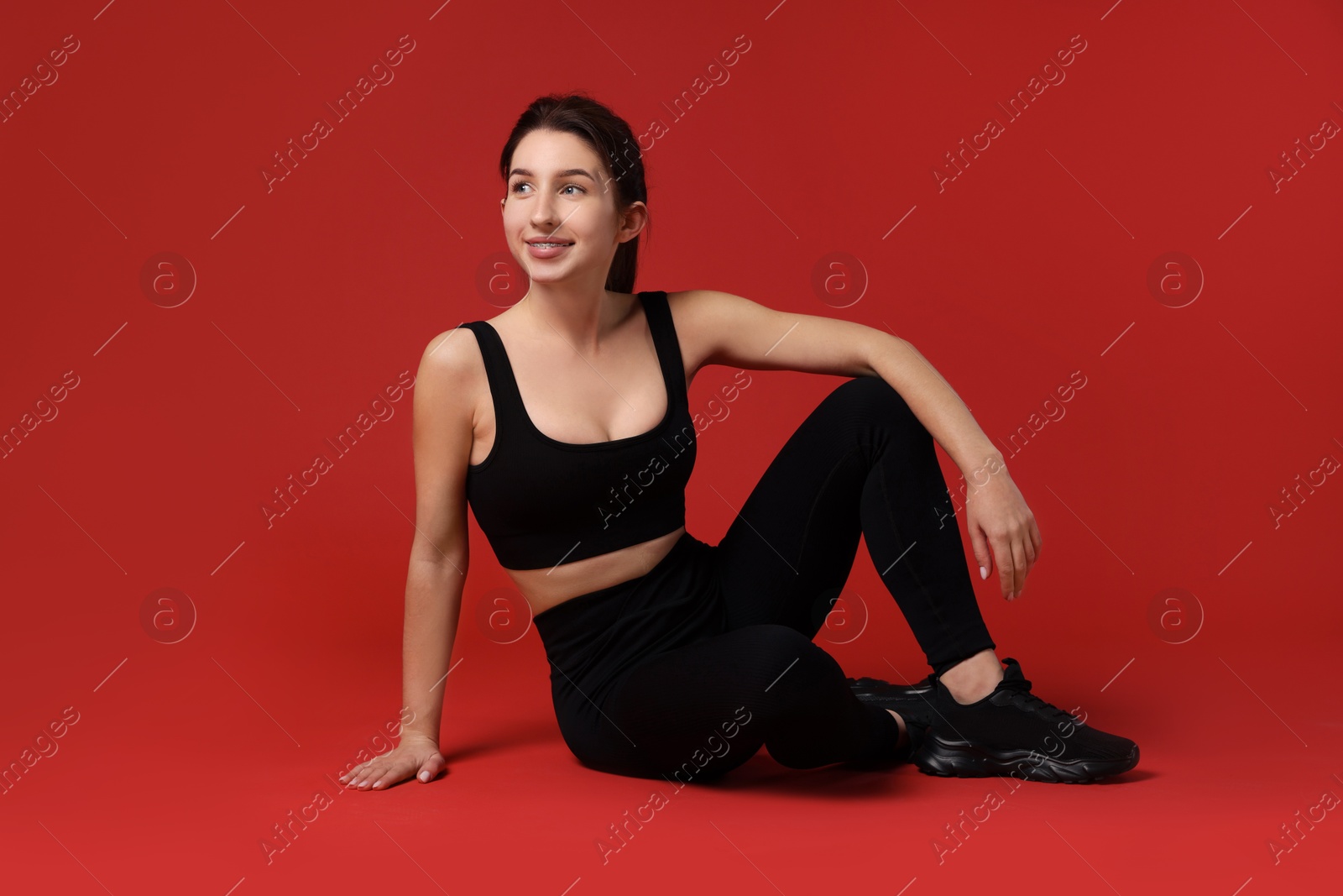 Photo of Portrait of woman in sportswear on red background