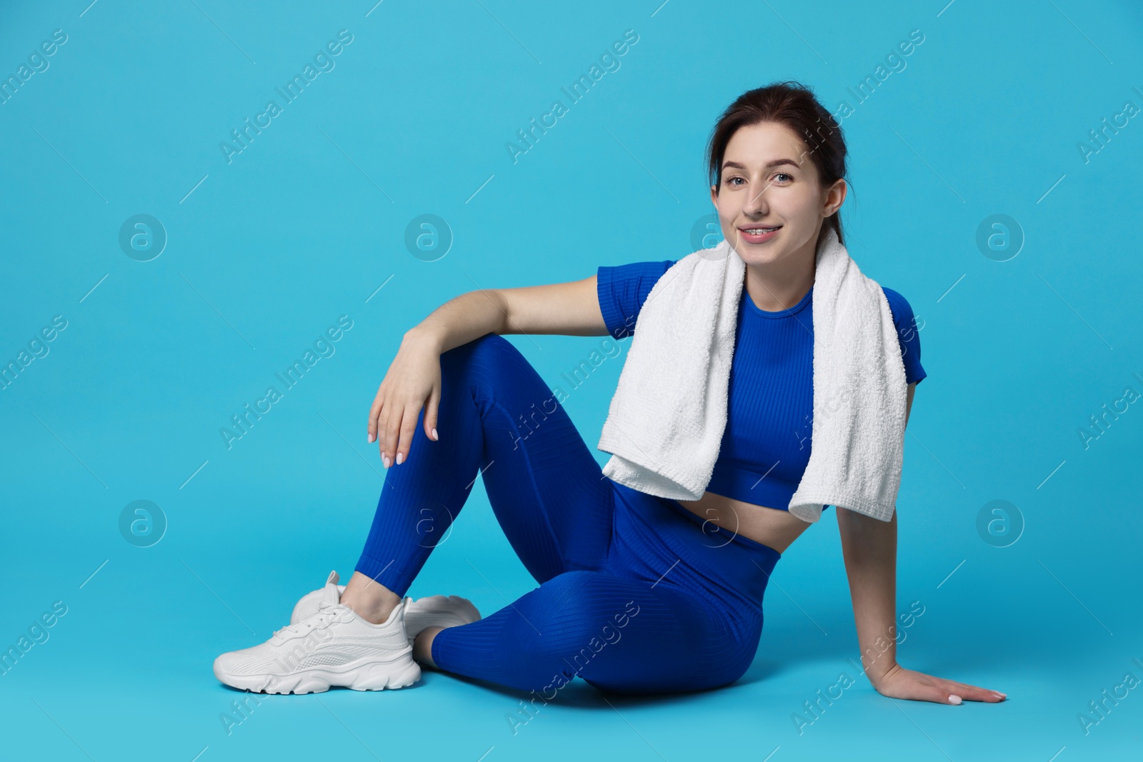 Photo of Woman in sportswear with towel on light blue background