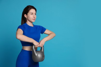 Photo of Woman in sportswear exercising with kettlebell on light blue background, space for text