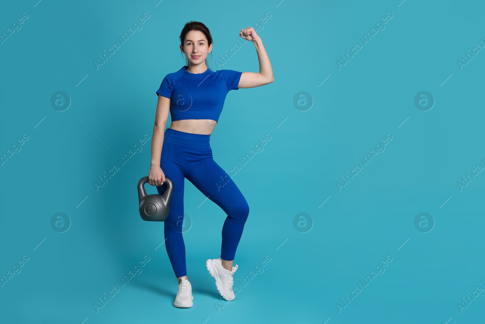 Photo of Woman in sportswear with kettlebell on light blue background