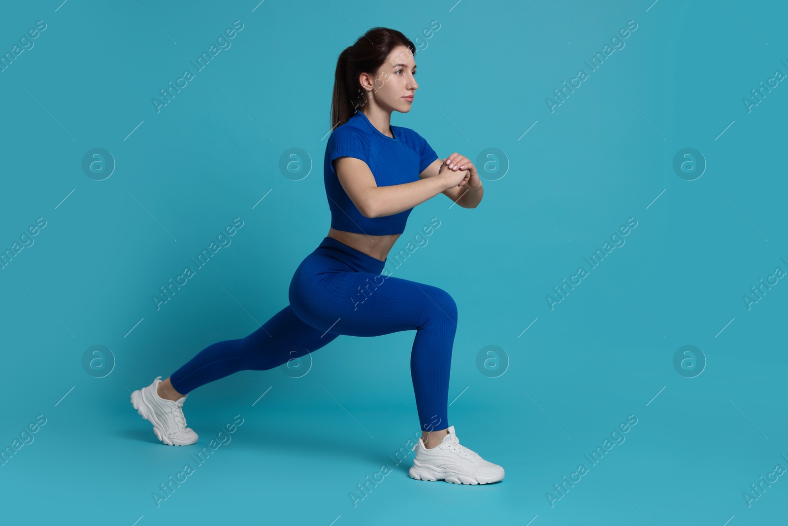 Photo of Woman in sportswear exercising on light blue background, space for text